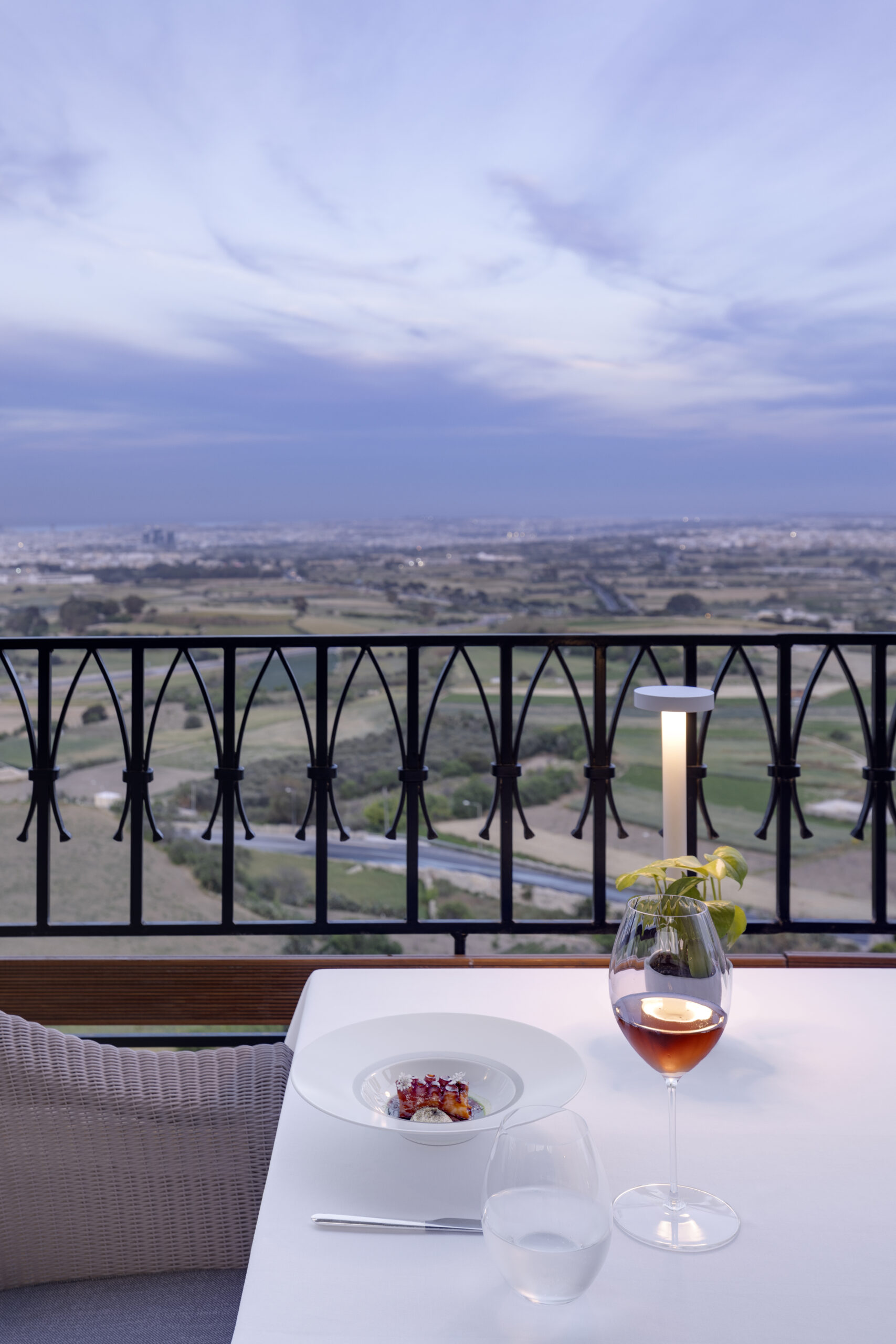 A table with a plate and wine glass on it, with a view behind it